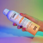 Imagen de una mano cogiendo el Isdin Spary Fotoprotector Wet Skin Transparente